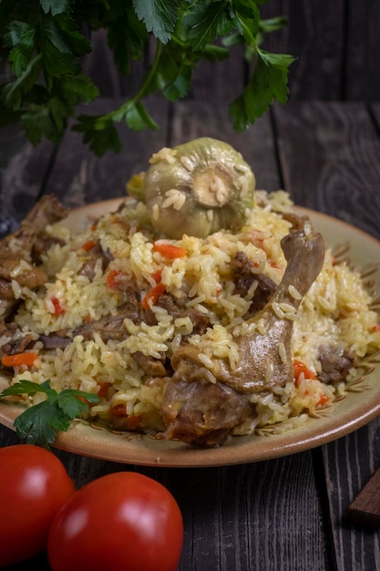 Uzbek pilaf with duck and garlic in a plate on a dark background