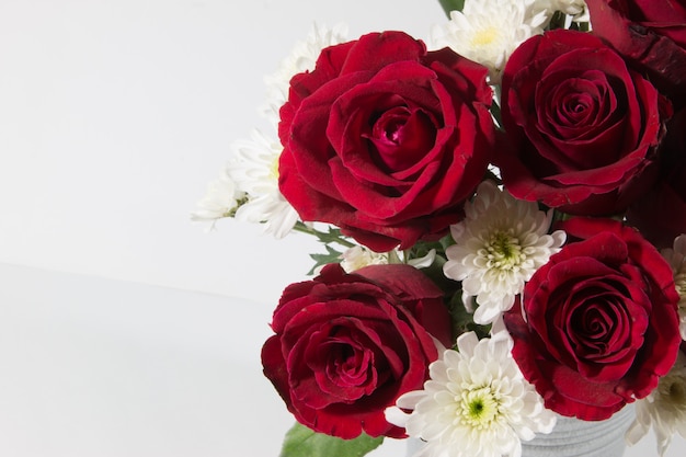 Vaas met boeket rode rozen in aluminium emmer op witte achtergrond.