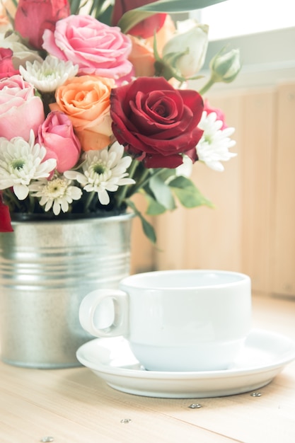 Vaas met boeket Rozen en witte kop koffie