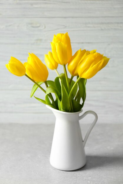 Vaas met boeket van mooie tulpen op gekleurde achtergrond
