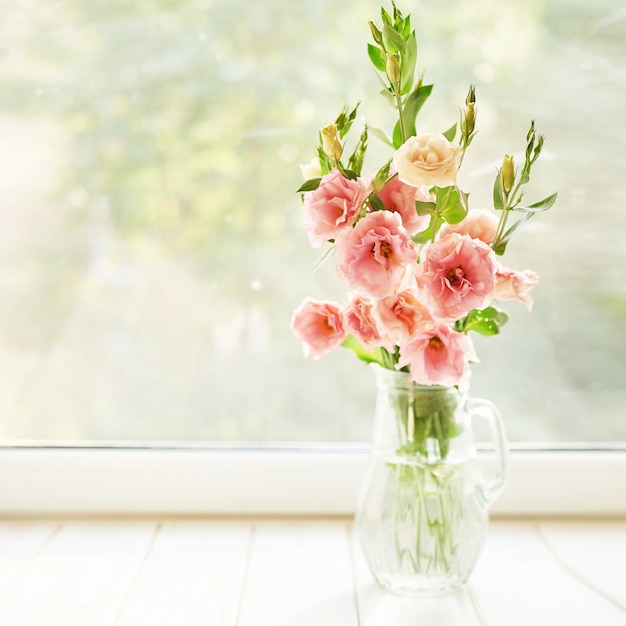 vaas met eustoma bloemen op een tafel tegen een raam