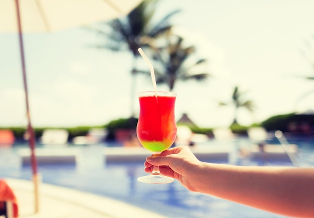 vacation, beverage and travel concept - close-up of female hand holding glass with cocktail