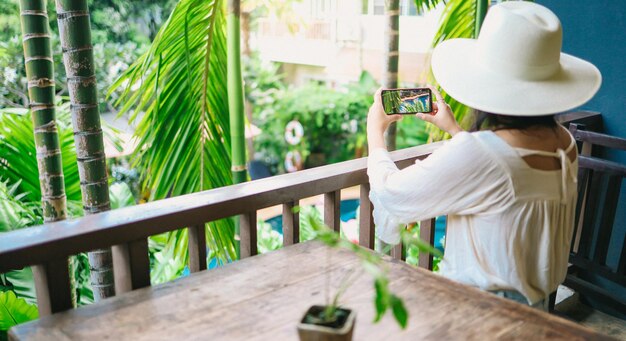 vacation concept Woman hand holding black smartphone relax at hotel resort enjoying luxury lifestyle outdoor