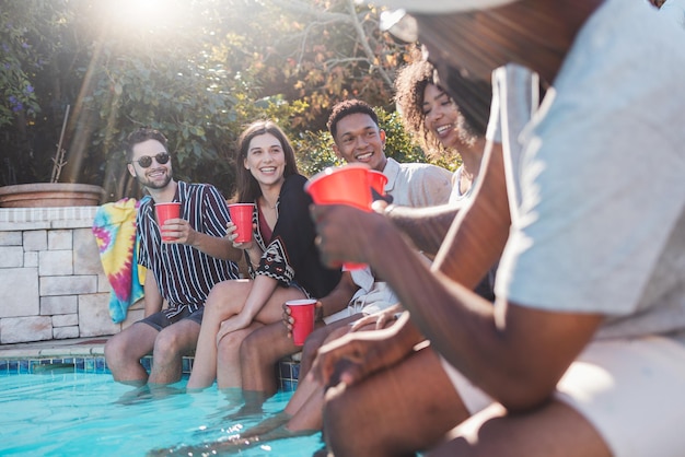 Vacation drinks and friends speaking in a pool at a summer party celebration or event at a home Diversity happy and people talking having fun and bonding by the swimming pool while drinking