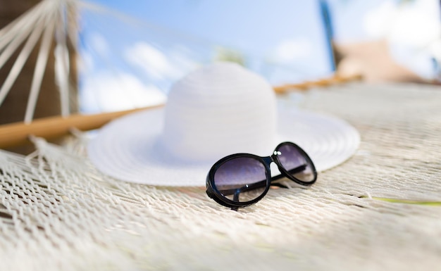 vacation and holiday concept - picture of hammock with white hat and sunglasses