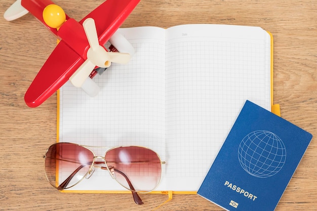 vacation planning concept in a diary with toy airplane, passport and sunglasses trailed around it