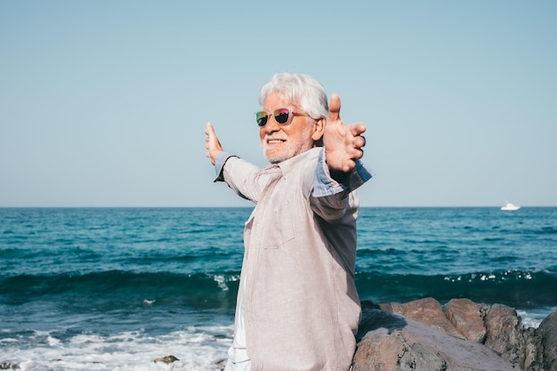 海での休暇退職ライフ スタイル コンセプト両手を広げた幸せな年配の男性