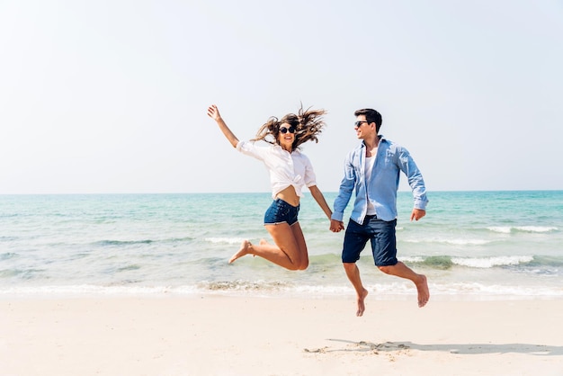 Vacation romantic love young happy smile couple in honeymoon travel holiday trip standing on sand at blue sky sea beach having fun and relaxing together on tropical beachSummer travel