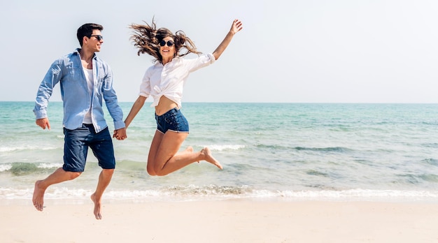 Vacanza romantica amore giovane sorriso felice coppia in luna di miele viaggio vacanza in piedi sulla sabbia al cielo blu mare spiaggia divertendosi e rilassandosi insieme sulla spiaggia tropicaleviaggi estivi