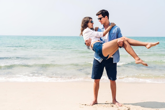 Vacation romantic love young happy smile couple in honeymoon travel holiday trip standing on sand at blue sky sea beach having fun and relaxing together on tropical beachSummer travel