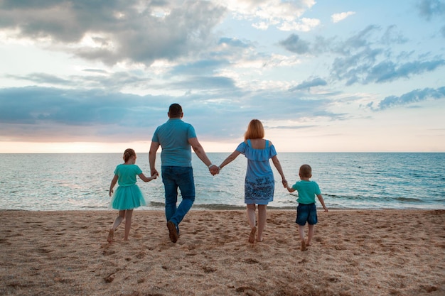 Vacanza al mare. una famiglia cammina lungo la spiaggia. famiglia che si tiene per mano