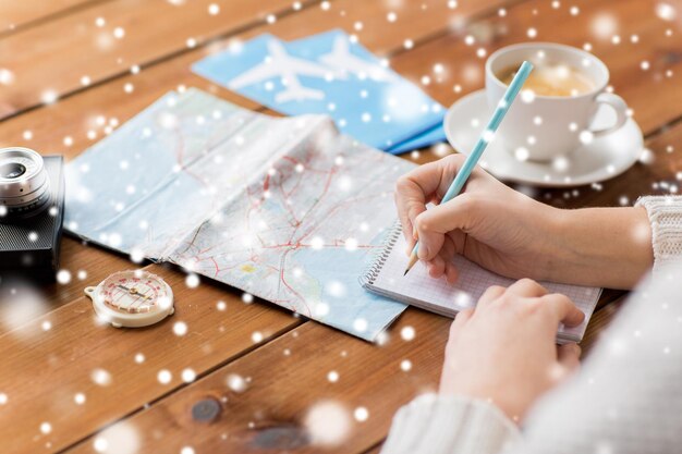 Photo vacation, tourism, travel, winter holidays destination and people concept - close up of traveler hands with blank notepad and pencil