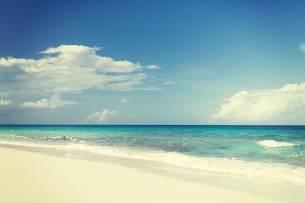 vacation, travel and background concept - blue sea or ocean, white sand and sky with clouds