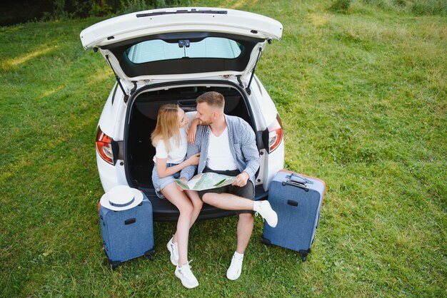 休暇、旅行-夏休みの旅行の準備ができている家族。スーツケースと車のルート。ロードトリップを計画している手に地図を持っている人。旅行のコンセプト。旅行者。