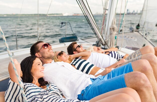 vacation, travel, sea, friendship and people concept - smiling friends lying on yacht deck