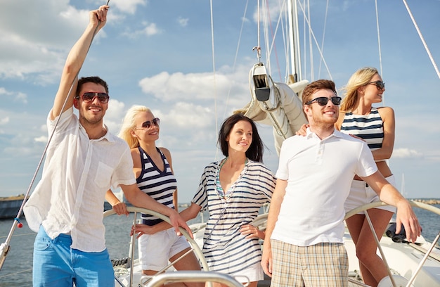 vacation, travel, sea, friendship and people concept - smiling friends sailing on yacht