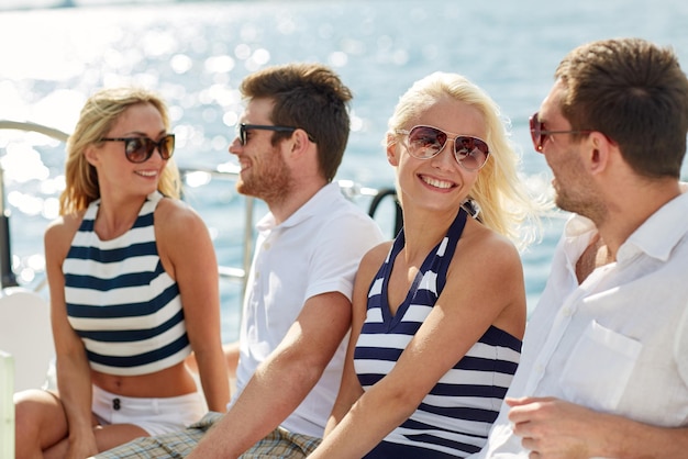 vacation, travel, sea, friendship and people concept - smiling friends sitting and talking on yacht deck