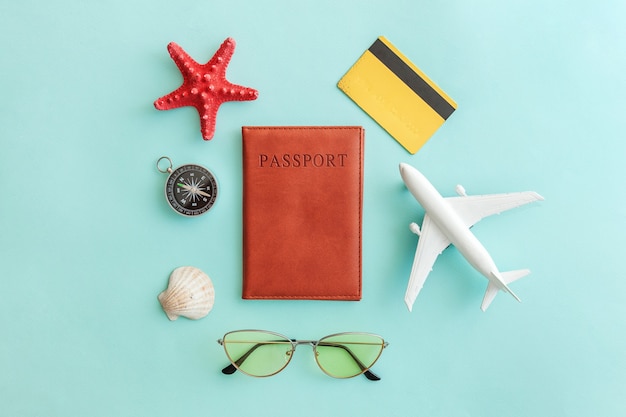 vacation travel trip concept. plane passport sunglasses compass gold credit card on blue background