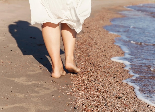 Vacation travel woman leg closeup walking on white sand relaxing in beach coverup pareo beachwear Sexy and tanned legs Sunmmer holidays weight loss or epilation pedicure concept