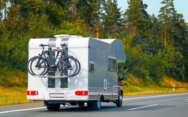 Vacation trip with Caravan Car with bicycle on road, Switzerland. Camper and Summer drive on highway. Holiday journey in rv motorhome for recreation. Motor home minivan motion ride on nature. Scenery.