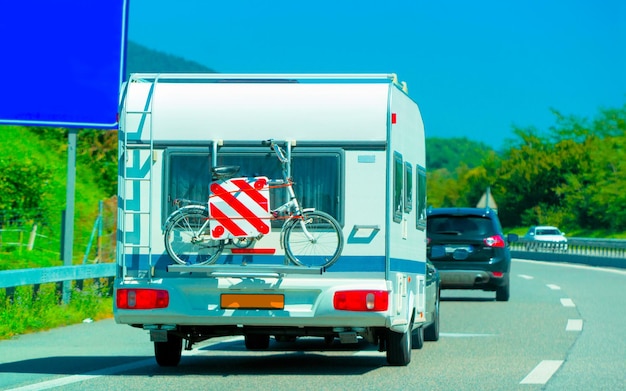 Vacation trip with Caravan Car with bicycle on road, Switzerland. Camper and Summer drive on highway. Holiday journey in rv motorhome for recreation. Motor home minivan motion ride on nature. Scenery.