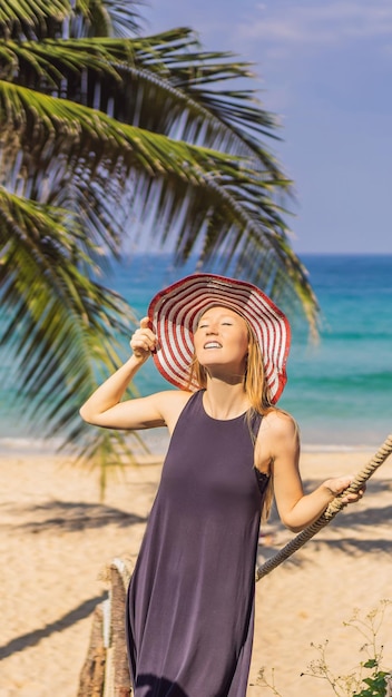 Vacation on tropical island woman in hat enjoying sea view from wooden bridge vertical format for