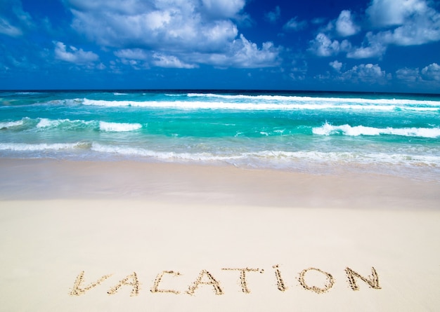 Vacation written in a sandy tropical beach