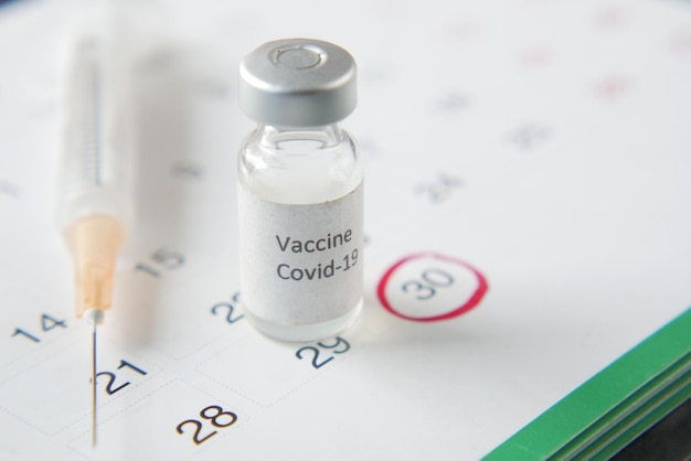 Vaccin dag concept glazen ampul met vaccin en spuit op kalender