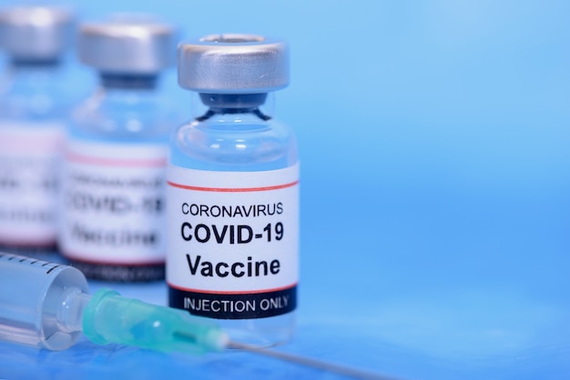 Vaccin en gezondheidszorg Medisch concept. Vaccins en spuit op blauwe achtergrond voor preventie, immunisatie en behandeling van coronavirusinfectie