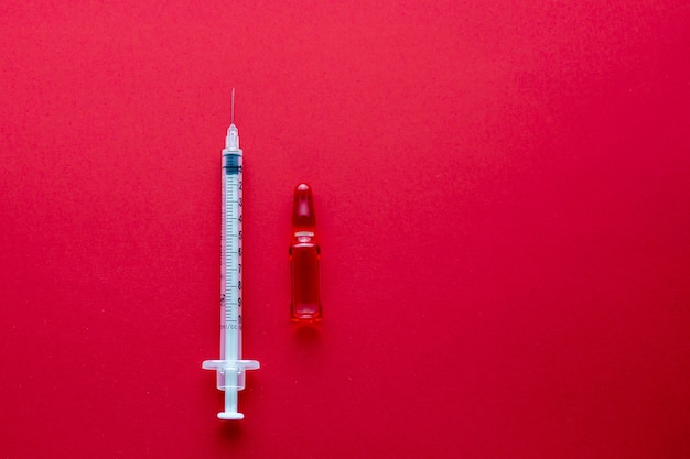 Vaccin met spuit op een rode achtergrond vitamine om de immuniteit te verbeteren antivirale injectie op een rode