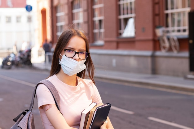 Studenti vaccinati tornano a scuola o all'università dopo la pandemia di covid19 su una ragazza adolescente con uno zaino e libri è in piedi accanto al cerotto medico dell'università a portata di mano