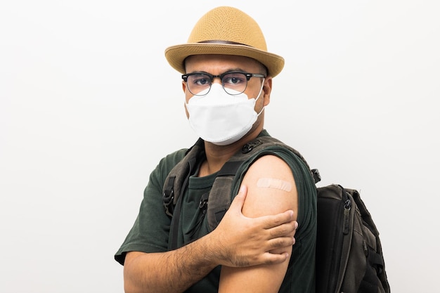 Vaccinated Traveler asian man wearing mask showing arm after coronavirus Vaccination isolated white Background Backpacker Indian man getting a vaccination covid19 immunization