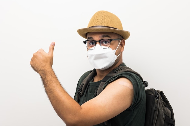 Vaccinated Traveler asian man wearing mask showing arm after coronavirus Vaccination isolated white Background Backpacker Indian man getting a vaccination covid19 immunization