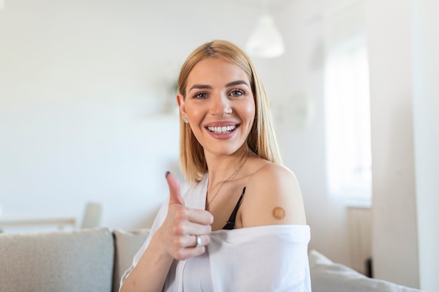 Vaccinated young Woman Gesturing Thumbs-Up Approving Vaccination, home Background