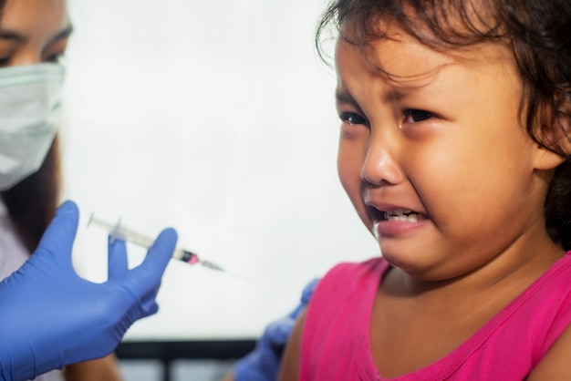 Vaccinatie. Arts die griepvaccin inspuiten aan kinder kleuterschool.