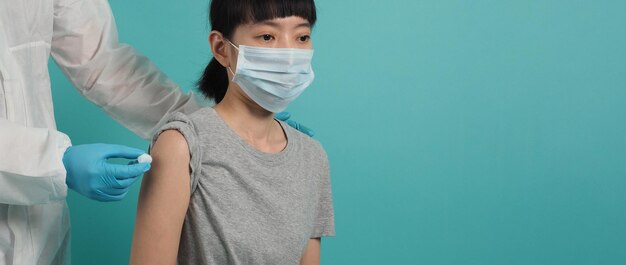 Vaccinatie immunisatie ziekte preventie concept. Vrouw met medisch gezichtsmasker die Covid 19 of griepvaccin krijgt. Arts die katoen voor en na maakt injectie gebruikt. Coronavirus gevaccineerde vrouw.