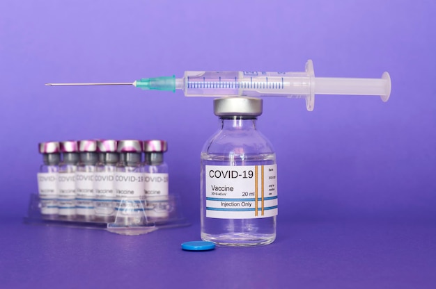 Foto vaccinatie tegen covid-19 coronavirus met het vaccin in de hand op paarse achtergrond