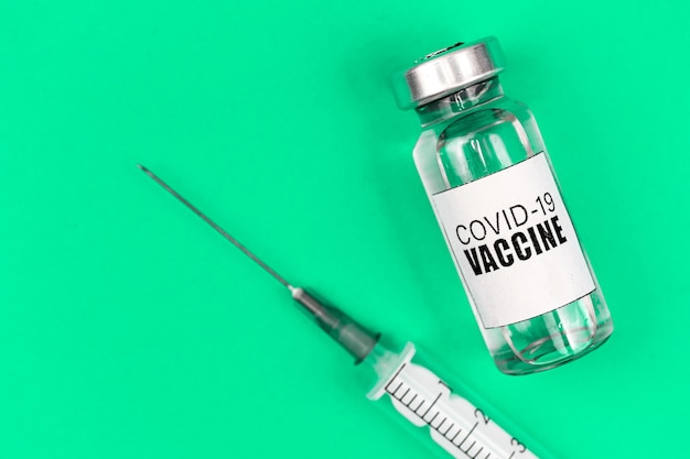 Vaccinatie tegen COVID-19 coronavirusachtergrond, met vaccinflacon en spuit