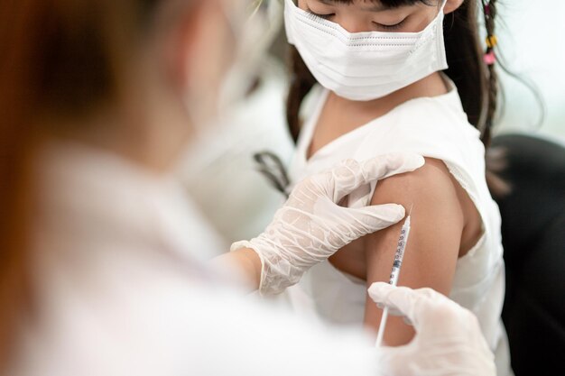 Foto vaccinatieconcept vrouwelijke arts die een schattig klein meisje in de kliniek vaccineert