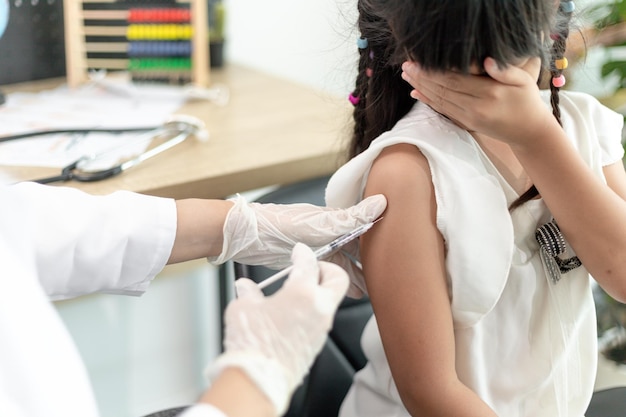 Vaccinatieconcept Vrouwelijke arts die schattig klein meisje in kliniek vaccineert