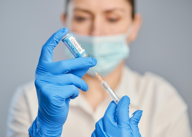 Vaccination against covid a doctor in blue gloves holds a syringe and an ampule with a vaccine