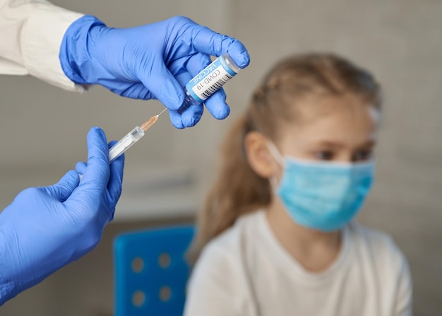 Vaccination of children A woman doctor makes injection with a syringe of a vaccine to a teenager