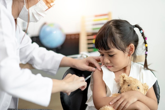 Vaccination concept Female doctor vaccinating cute little girl in clinic