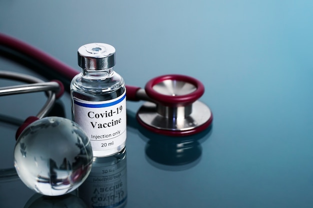 Concetto di vaccinazione globo di vetro con bottiglia di vaccino sfocata stetoscopio medico
