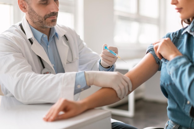 Vaccination concept young woman getting vaccinated against viruses in hospital male doctor giving