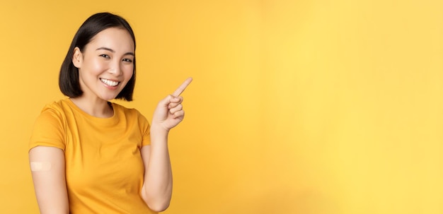 Vaccination and covid pandemic concept smiling korean woman with band aid on shoulder after coronavi