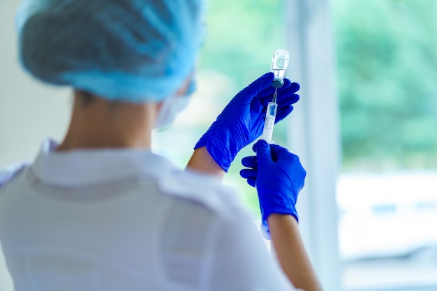 Vaccination of people during an epidemic and viral infectious diseases. Nurse using syringe for injection of an antibiotic to a patient in a hospital. Flu shot