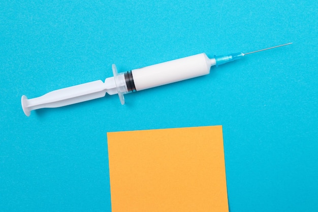 Концепция вакцинации или ревакцинации медицинский шприц на синем столе
