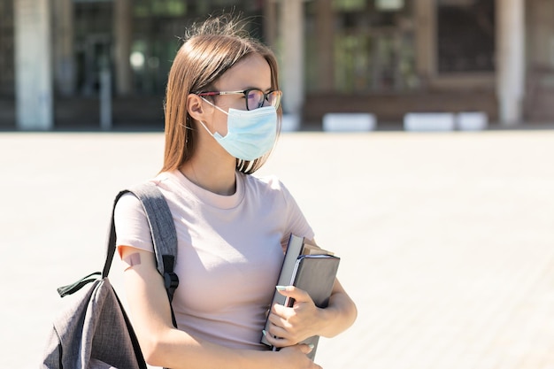 Vaccination in schools and collegesteenage student in a medical mask with medical plaster on hand stands next to the university