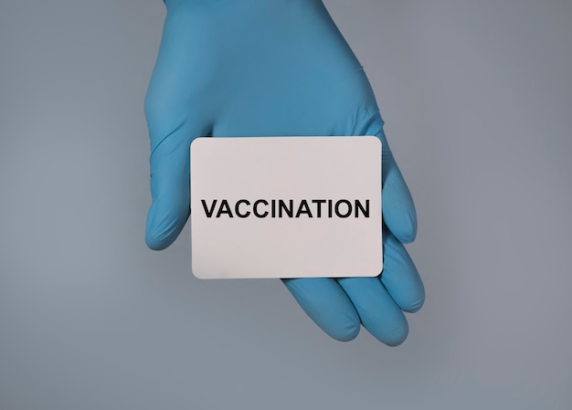 Слово о вакцинации на бумаге в руке в латексных перчатках для предотвращения вируса